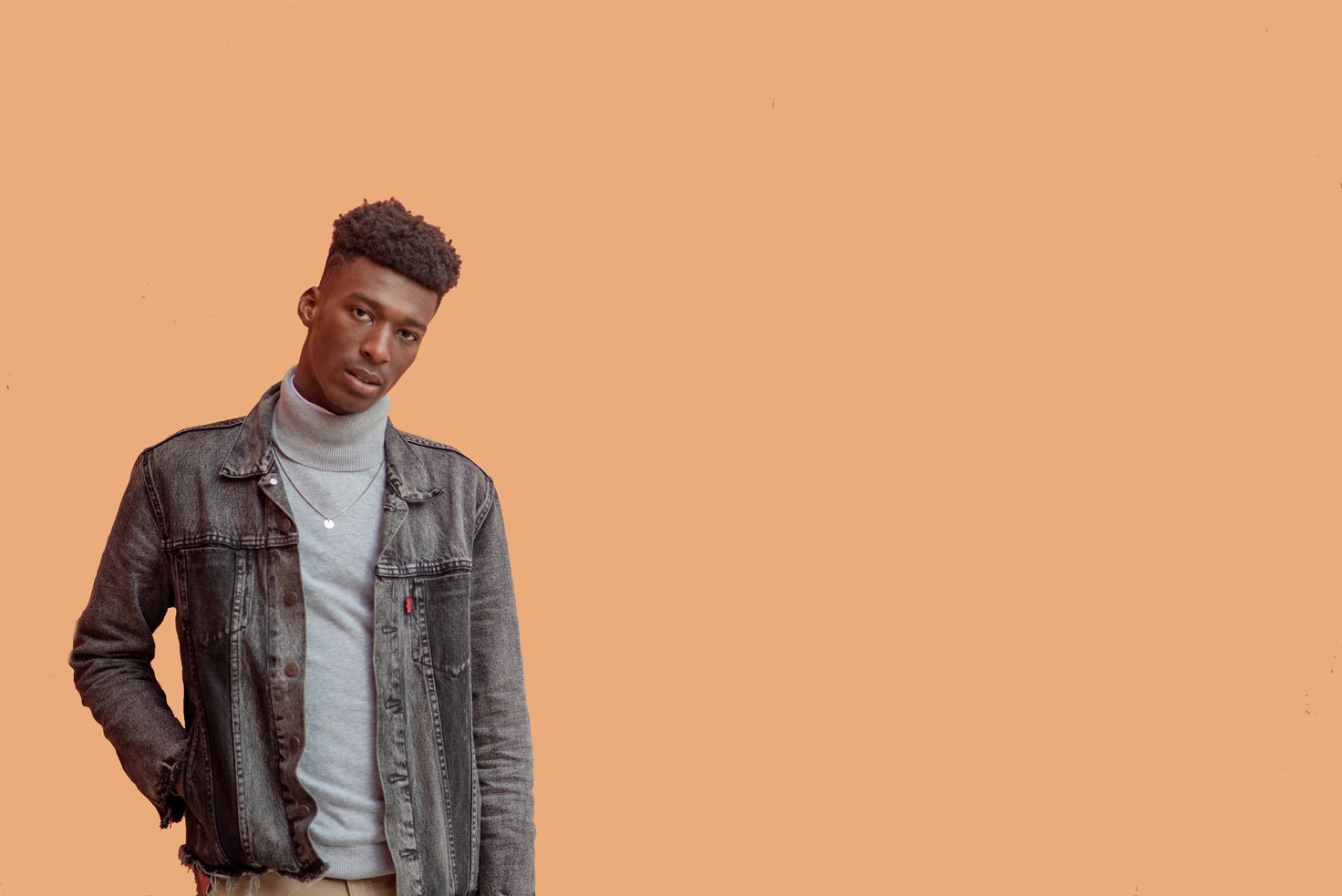 Man in Gray Denim Jacket Standing Near Orange Wall